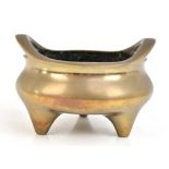 A Chinese bronze censer with raised pierced handles, three simple tapering supports and impressed
