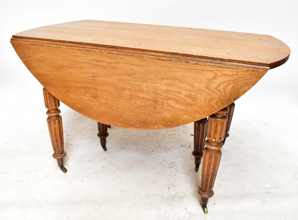 A late 19th century French oak extending dining table with rounded rectangular top on fluted legs to