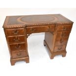 A mid-20th century kneehole mahogany desk, the top inset with tooled brown leather sections above