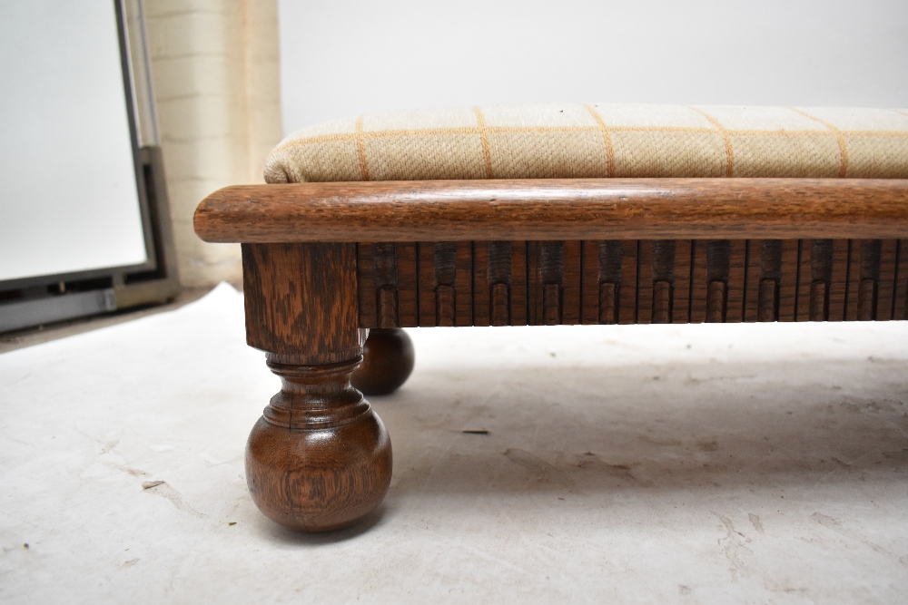 An oak long low stool with padded squab, carved frieze and raised on turned supports, length 140cm. - Image 2 of 3