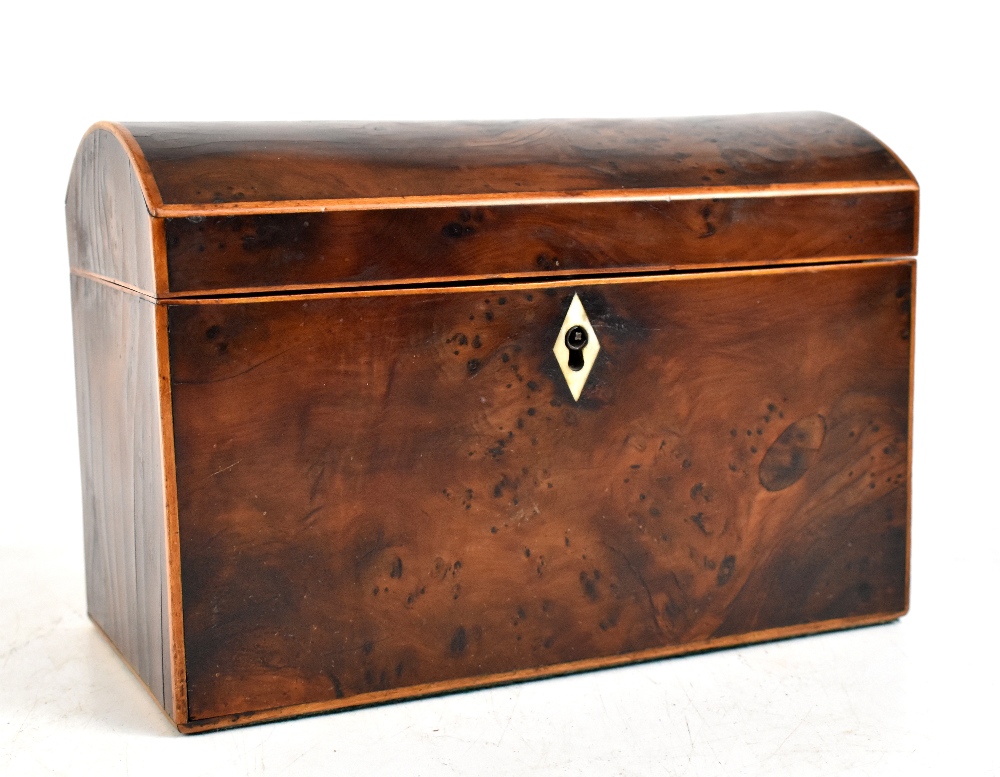 An early 19th century yew wood dome topped tea caddy, the hinged cover enclosing two compartments,