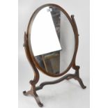 An Edwardian mahogany oval swing toilet mirror on serpentine supports and outswept feet (af),