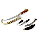 A Middle Eastern dagger with curved blade, the wooden handle embellished with brass,