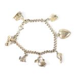 A sterling silver charm bracelet with various charms to include a dog, a tractor and a boot.