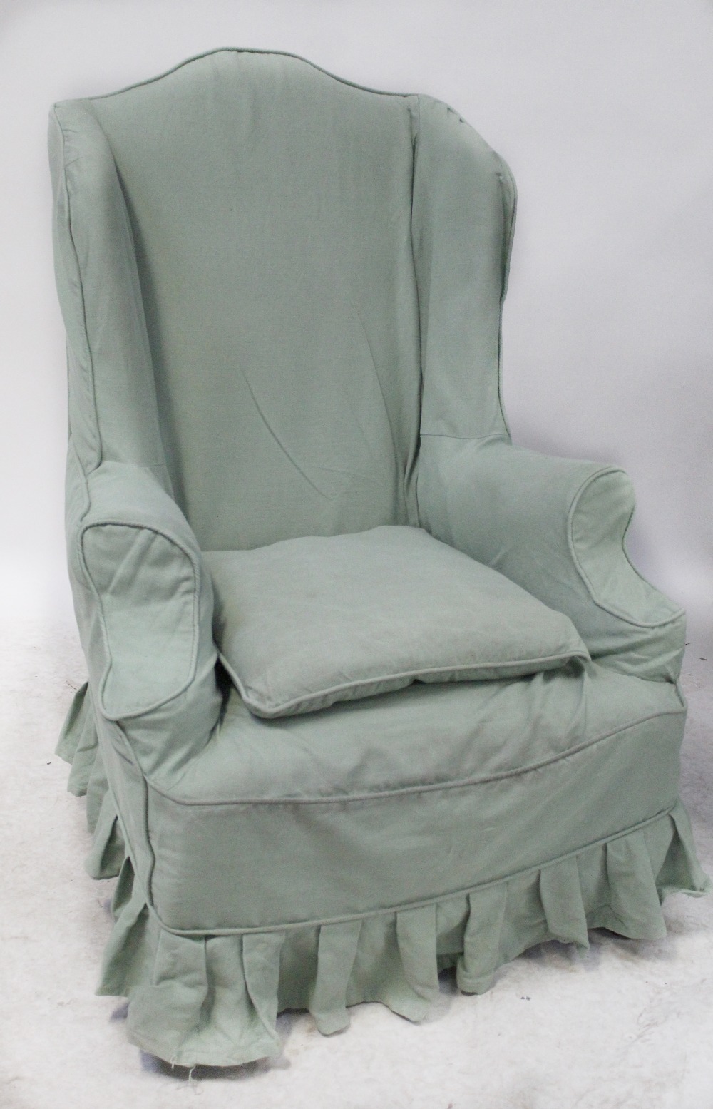 A Georgian-style oak wingback armchair with outswept arms,