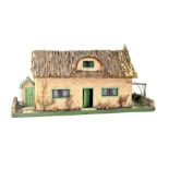 A dolls' house in the form of a cottage with straw-effect thatched roof,