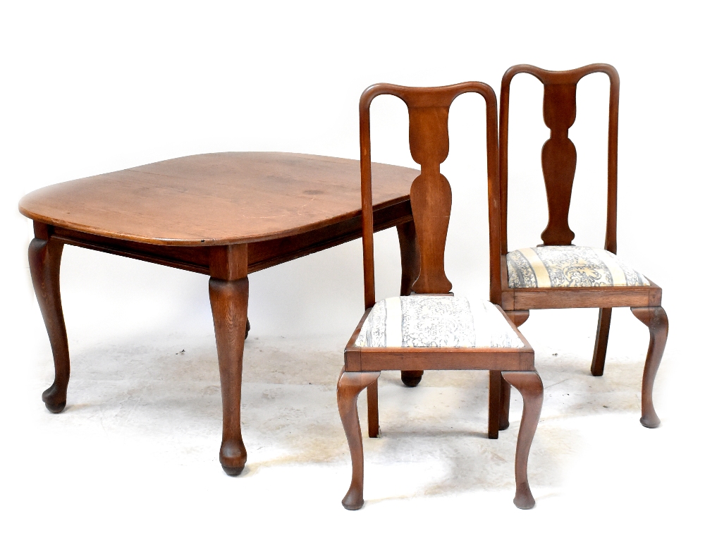 An early 20th century oak extending dining table with one extra leaf, on cabriole legs,