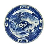 A Chinese blue and white porcelain charger depicting figures on a bridge within a mountainous
