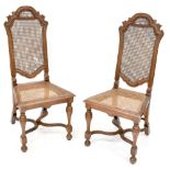 A pair of 17th century style walnut cane-seated dining chairs with arched tops and X-frame