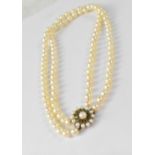 A two-strand cultured pearl necklace with a 9ct gold floral clasp set with small green stones and