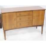 A 1950s walnut sideboard with three central drawers flanked by cupboard doors,