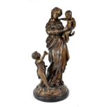 A bronze figure group depicting a mother carrying a child with one other standing at her feet,