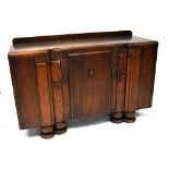 A 1930s oak sideboard comprising central cupboard enclosing two cutlery drawers flanked by cupboard