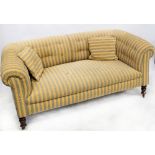 A Victorian sofa with deep button back to scrolling arms, on mahogany turned supports and castors,