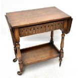 A 1920s carved oak two tier trolley, with two side flaps and frieze drawer above a galleried under