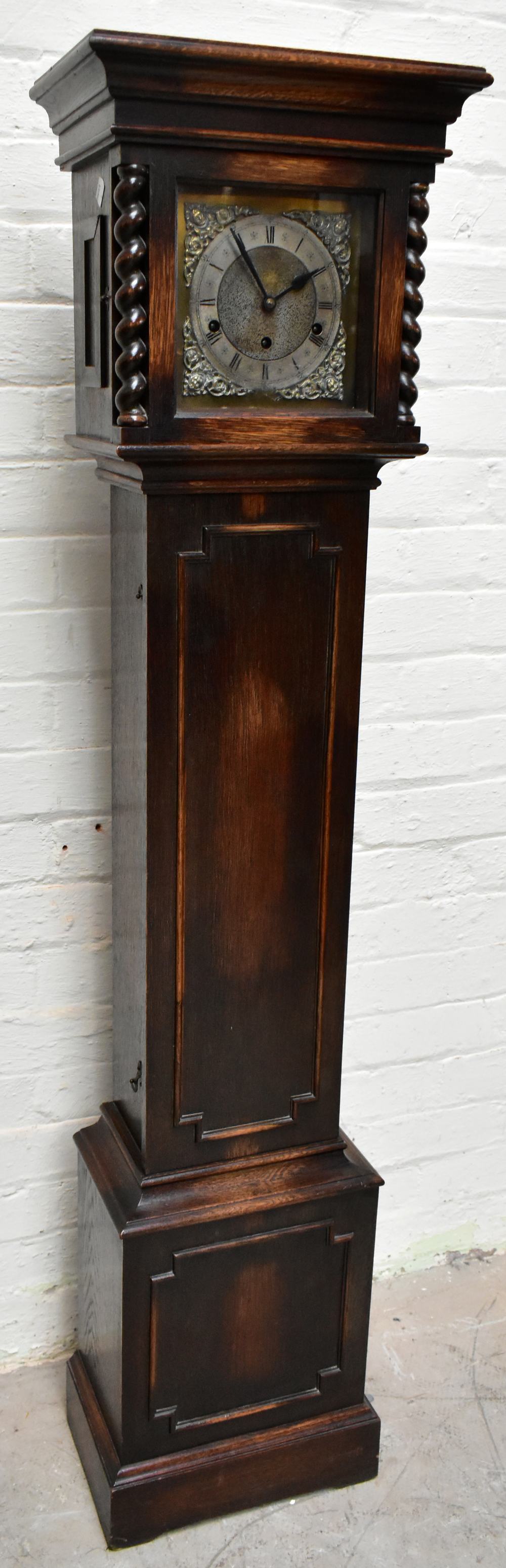 An early 20th century oak cased longcase clock of small proportions, the brass face with applied