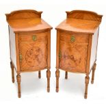 A pair of Edwardian Sheraton Revival painted satinwood bowfront bedside cabinets, with raised