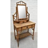 An early 20th century bamboo mirror back dressing table, with two drawers raised on column supports,