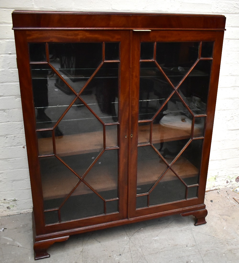 An early 20th century mahogany bookcase, the pair of astragal glazed doors, enclosing an arrangement