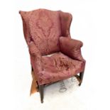 A 19th century wingback armchair upholstered in a maroon floral material, raised on tapering block