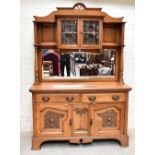 An Arts and Crafts golden oak high back dresser with two curved doors with leaded bowed glass