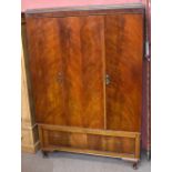 An early 20th century mahogany wardrobe, with three doors above a base drawer, on bracket feet,