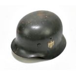 A German WWII Wehrmacht helmet bearing eagle and swastika decal, retaining leather liner and