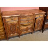 A carved walnut sideboard, with two bow front drawers above a small double panelled cupboard door,