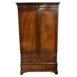 An early 20th century mahogany twin door wardrobe, the pair of panelled doors above two short and