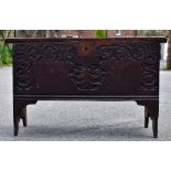 An 18th century carved oak plank top coffer, with carved decoration and carved date of 1676,