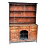 A George III oak dresser with associated stained pine boarded rack above an central dog kennel and