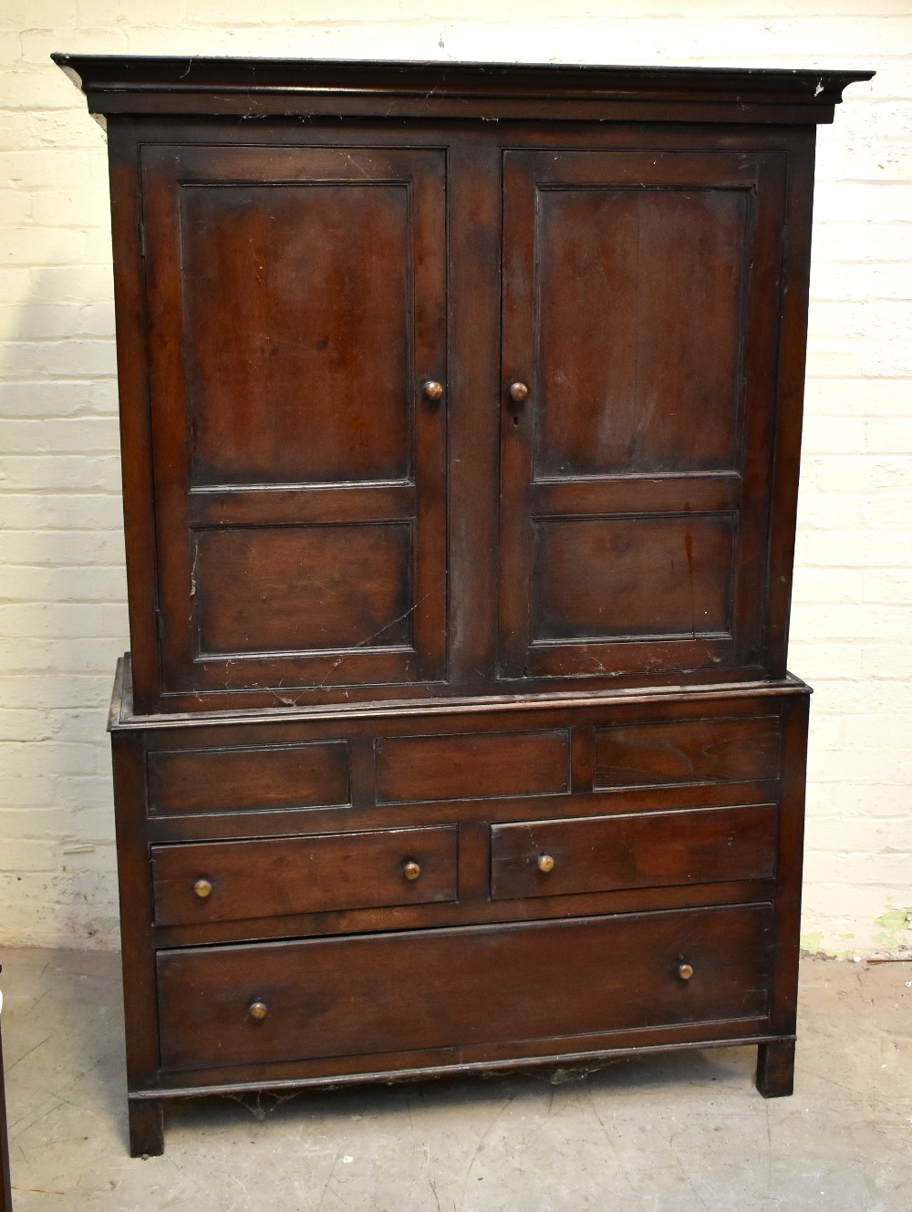 A 19th century oak cupboard on stand, the twin panelled doors an arrangement of hooks, above two