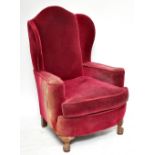 An early 20th century wingback armchair, upholstered in a red material, raised on ball and claw