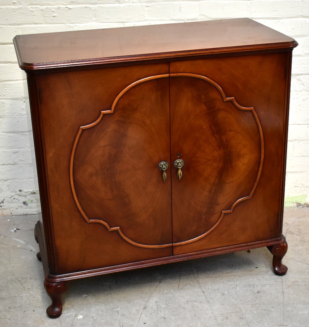 WARING & GILLOWS; a mahogany twin door cupboard raised on cabriole supports, length 100cm, depth