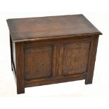 A reproduction oak blanket box with carved detail to the front panels, raised on block supports,