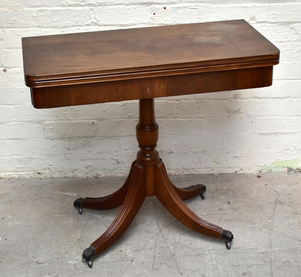 A reproduction mahogany veneered fold-over card table, raised on baluster from supports