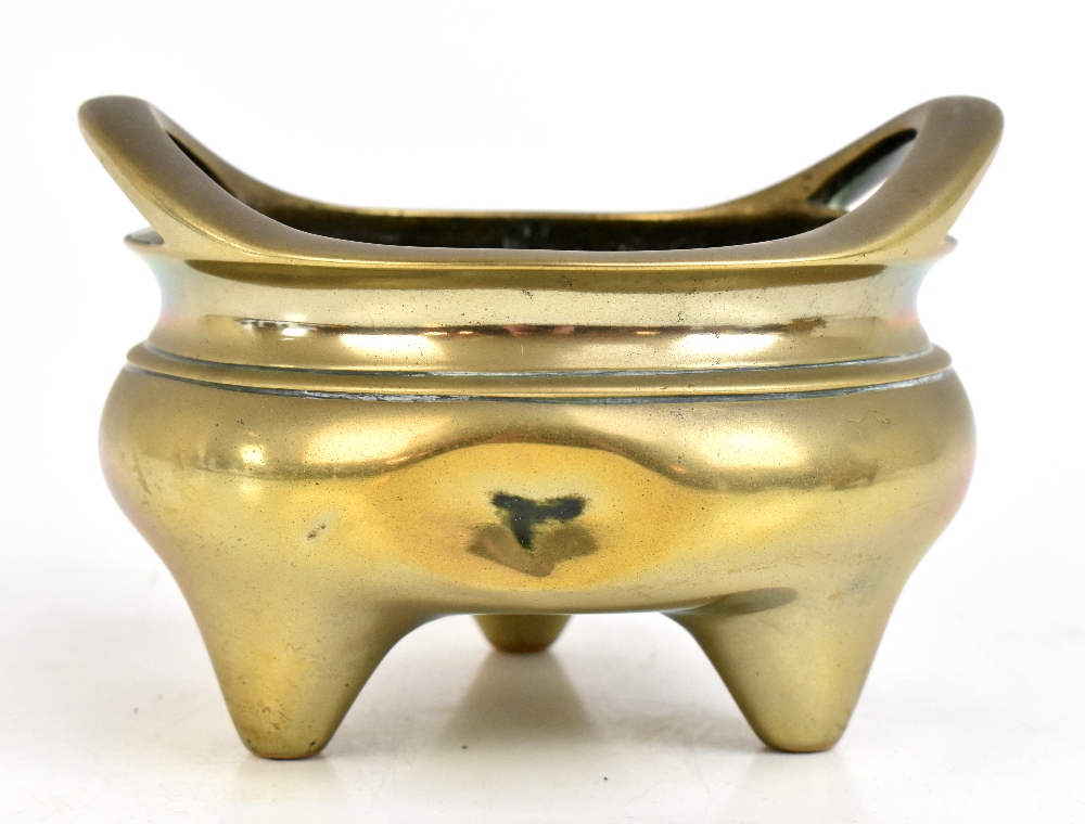 A Chinese bronze censer with pierced twin raised handles and three simple tapering supports,