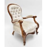 A Victorian walnut spoon back armchair of serpentine outline with carved detail to knees on