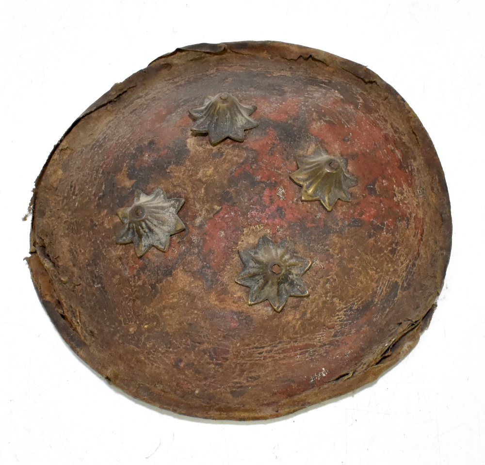 An Indian hide covered dahl shield with applied brass devices, for restoration, diameter 26.5cm.