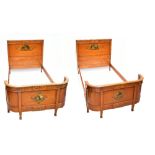 A pair of Edwardian Sheraton Revival painted satinwood single beds, the headboards and curved
