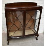 A 1930s walnut two door display cabinet with shaped astragal glazed doors enclosing glass shelves on