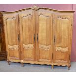 A modern and large French carved oak armoire, with moulded cornice above four double panelled doors,