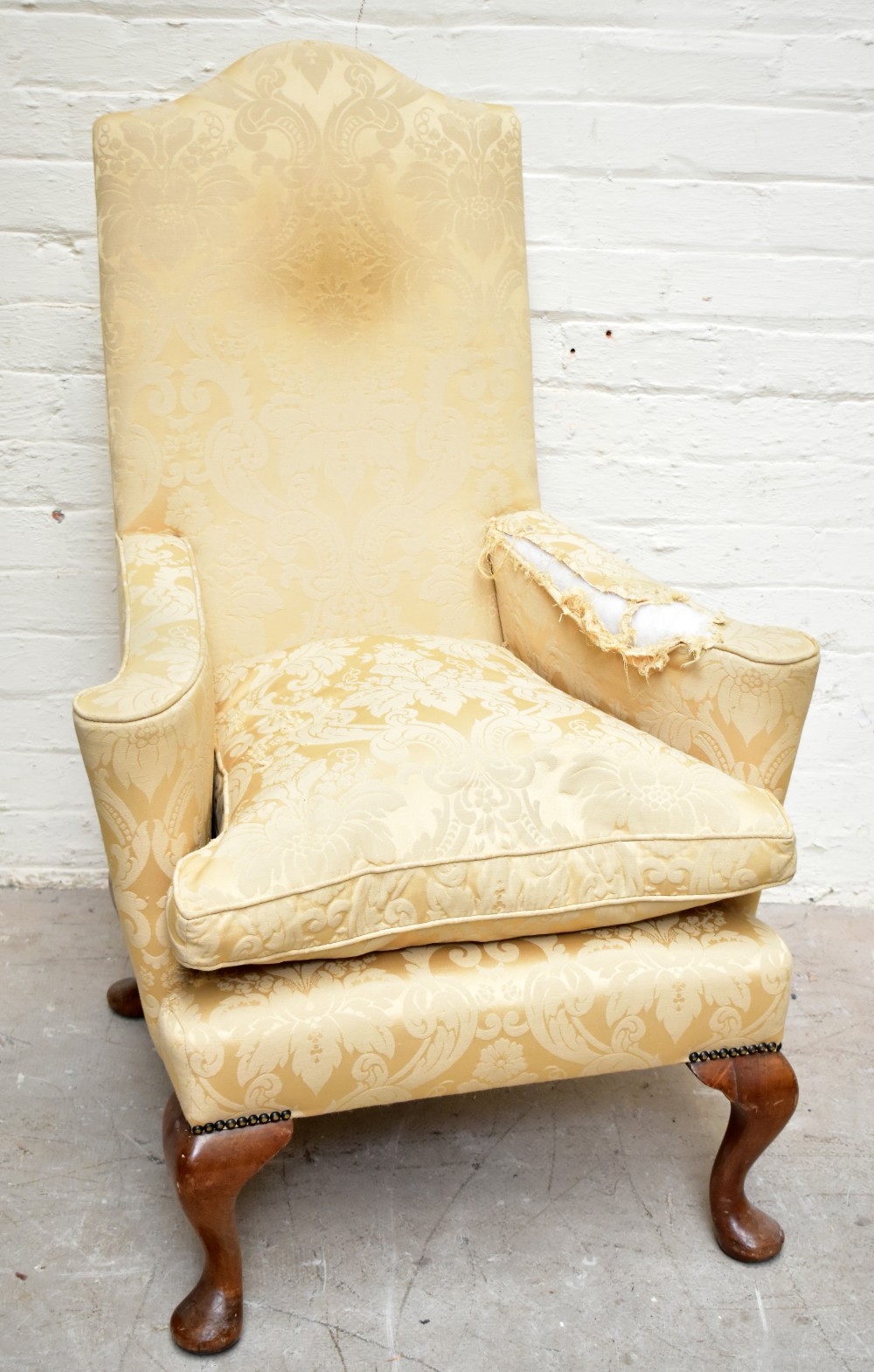 A George II style wing back chair, with floral yellow upholstery, on cabriole legs, height 112cm.