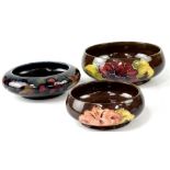 Three Moorcroft bowls, two brown ground with tube-lined hibiscus decoration,