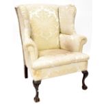 A 19th century mahogany wing back armchair upholstered in a cream sateen fabric,
