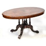 A Victorian walnut oval tilt-top table on four turned column base, with outswept carved legs,