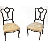 A pair of Victorian ebonised bedroom chairs with pierced splats and overstuffed seats,