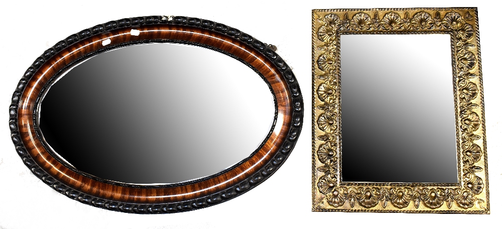 An ebonised and walnut framed oval wall mirror with bevelled plate,