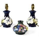 A pair of Moorcroft short lamp bases decorated with white tube-lined 'Hibiscus' pattern on a blue