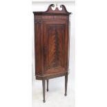 A 19th century mahogany floorstanding corner cupboard with broken swan neck pediment above a single